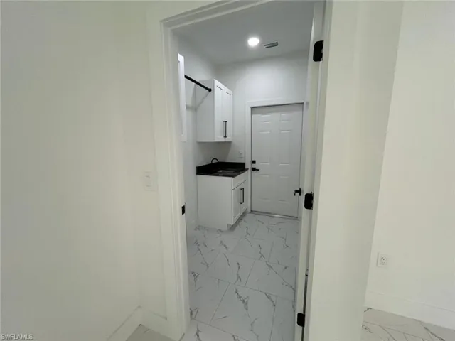 Laundry area with light marble finish flooring and recessed lighting