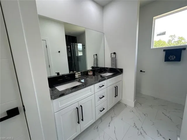 Bathroom featuring double vanity, a shower stall, and marble finish floors