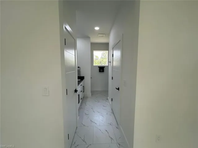 Hall featuring light marble finish floors and recessed lighting