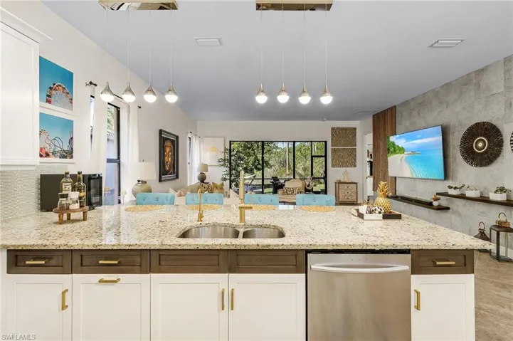 Kitchen featuring white cabinets, light stone countertops, dishwasher, and pendant lighting