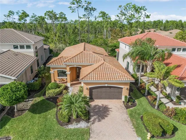 Mediterranean / spanish house with stucco siding, a garage, a tiled roof, and decorative driveway