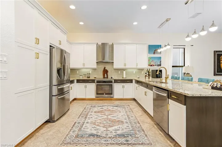 Kitchen with open shelves, a peninsula, appliances with stainless steel finishes, hanging light fixtures, and light stone countertops