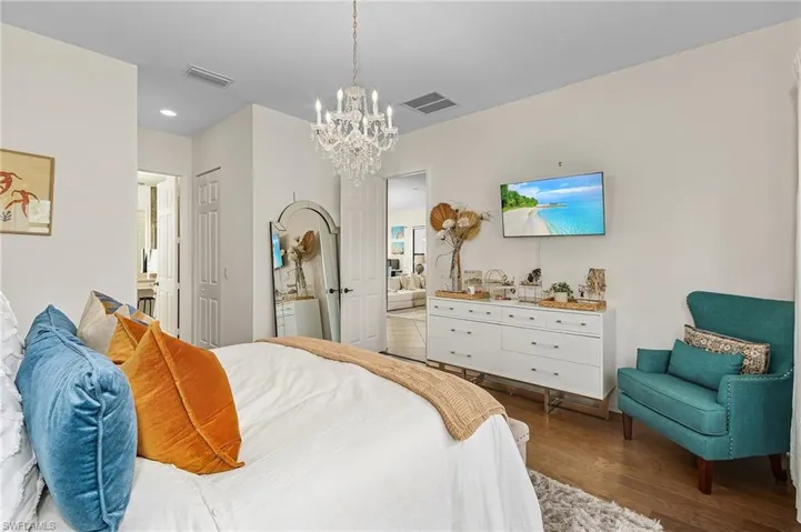 Bedroom with ensuite bathroom, dark wood-type flooring, a chandelier, a closet, and recessed lighting