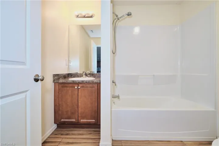 Full bath featuring vanity, bathtub / shower combination, and light wood-style floors