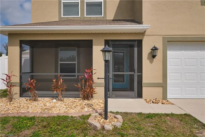 Property entrance featuring stucco siding, a sunroom, and an attached garage