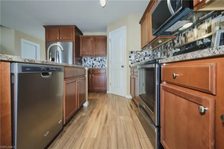 Kitchen with stainless steel appliances, wood finish cabinets, and light wood-type flooring