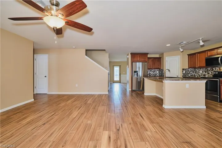 Kitchen featuring decorative backsplash, stainless steel appliances, open floor plan, a kitchen island with sink, and ceiling fan
