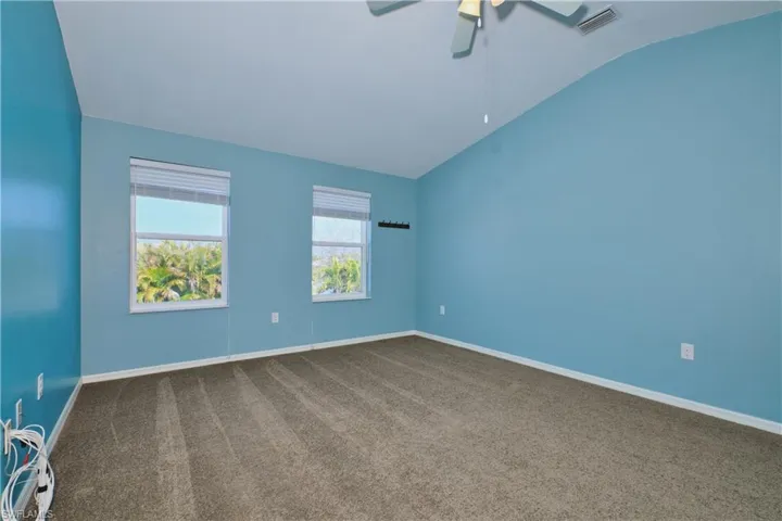 Spare room with carpet floors, vaulted ceiling, and a ceiling fan