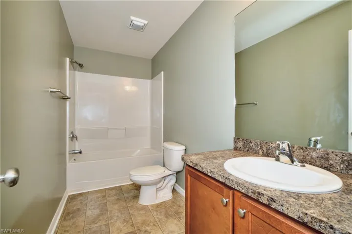 Bathroom with vanity, bathing tub / shower combination, and light tile patterned flooring