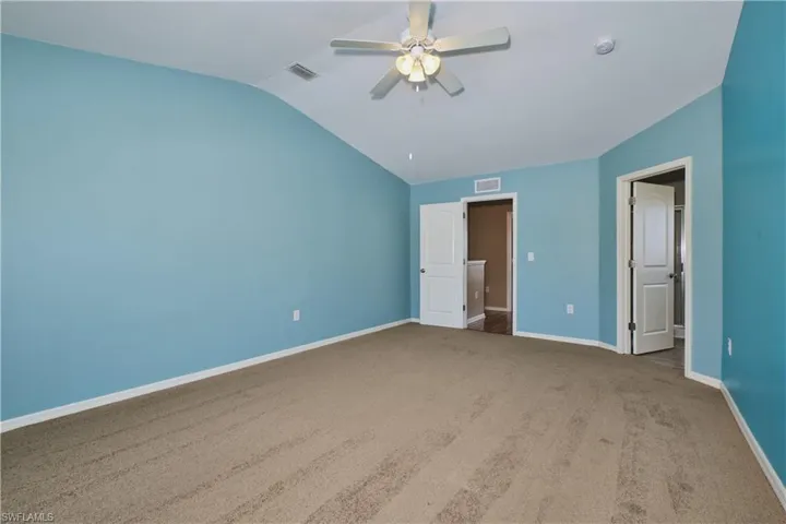 Unfurnished bedroom featuring carpet, a ceiling fan, and lofted ceiling