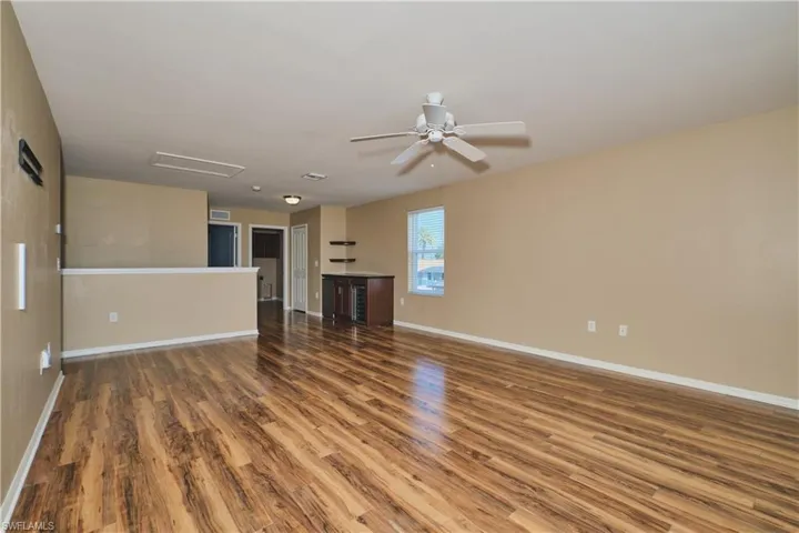 Unfurnished living room with dark wood-style flooring and ceiling fan