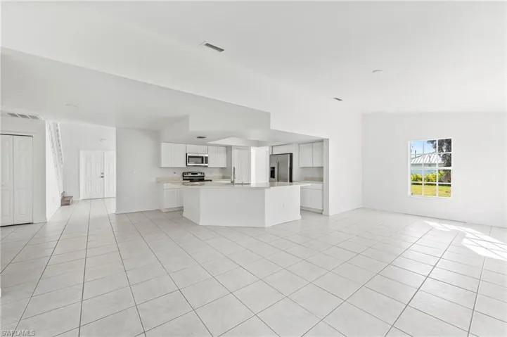 Unfurnished living room / Dining area with vaulted ceiling, sink, and light tile patterned floors