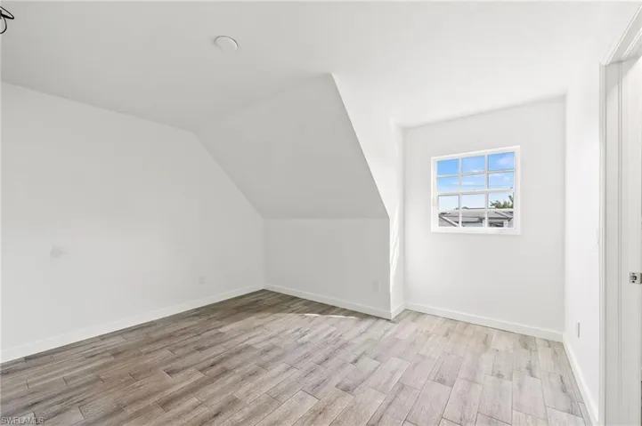Bedroom featuring light tiled / wood-style flooring and lofted ceiling