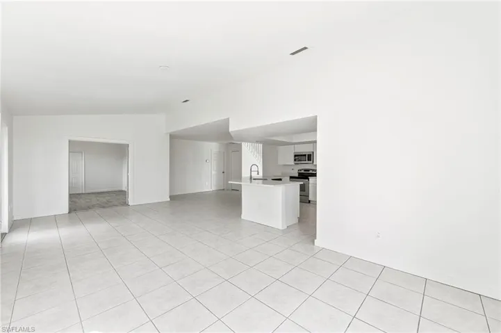 Unfurnished living room / Dining area with light tile patterned floors, vaulted ceiling, and sink
