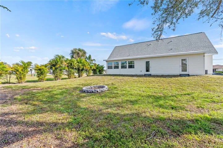 Back of property with a fire pit and a lawn