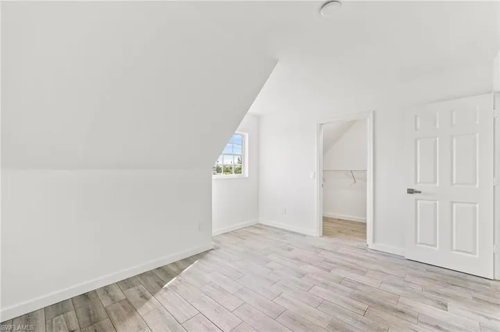 Bedroom with light tiled / wood-style flooring and vaulted ceiling