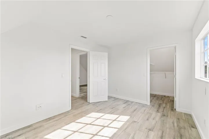 Bedroom featuring light tiled / wood-type flooring, a walk in closet, and a closet