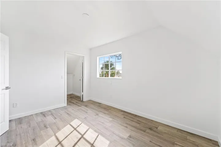 Bedroom featuring light tiled / wood-style flooring, lofted ceiling, a closet, and a spacious closet