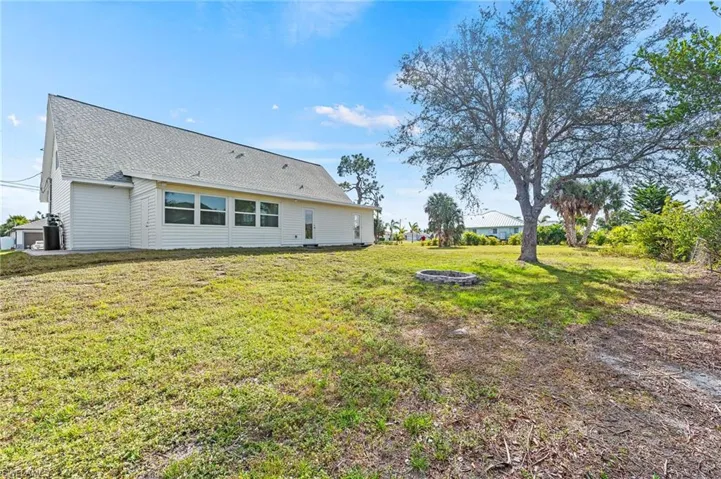 Rear view of property with a lawn and an outdoor fire pit