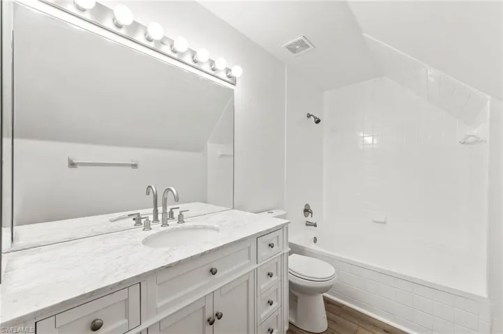 Main bedroom bathroom featuring vanity, tile / wood-style flooring, tiled shower / bath combo.