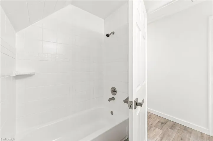 Guest bathroom featuring tiled shower / bath combo and tiled / wood-style floors