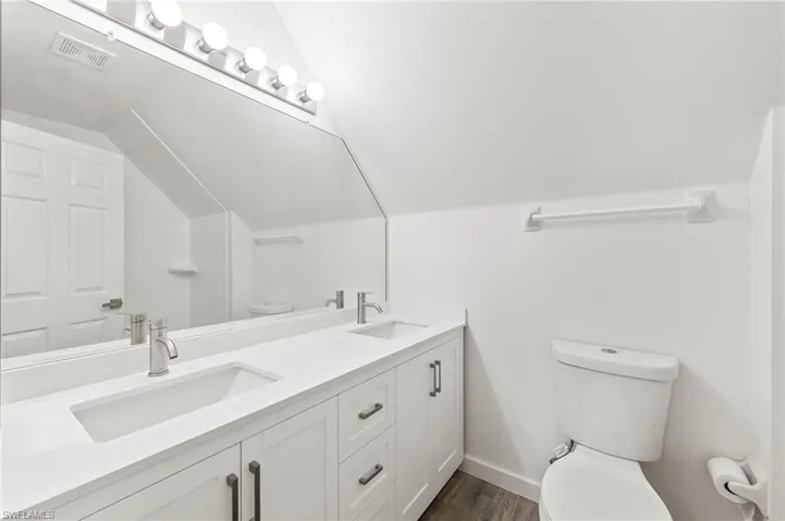 Guest bathroom featuring vaulted ceiling, new vanity, and tiled / wood-style flooring