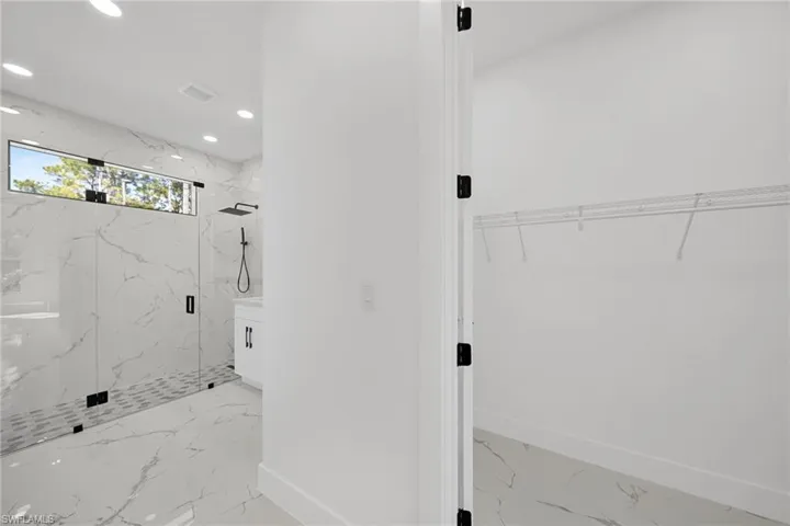 Full bath featuring a walk in closet, a marble finish shower, recessed lighting, and light marble finish floors