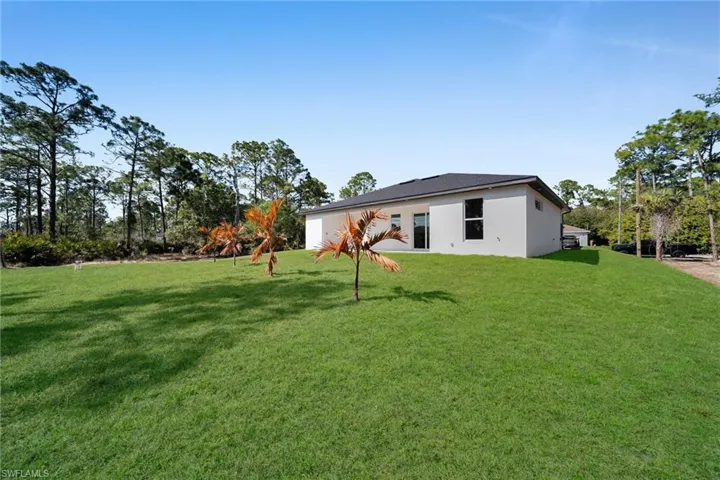 Rear view of house with a lawn and stucco siding