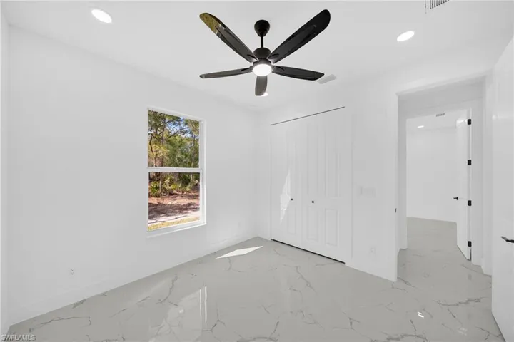 Unfurnished bedroom featuring recessed lighting, light marble finish floors, a closet, and a ceiling fan