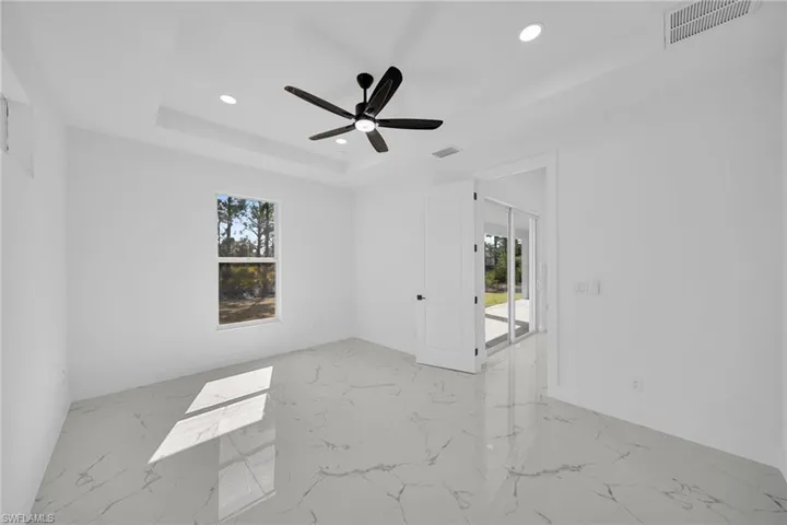 Unfurnished room featuring recessed lighting, light marble finish floors, ceiling fan, and a raised ceiling