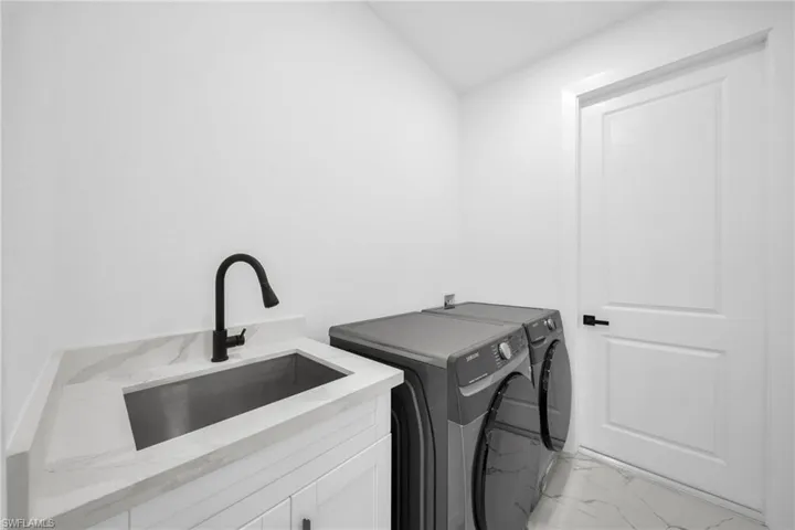 Laundry area featuring light marble finish flooring and washer and dryer