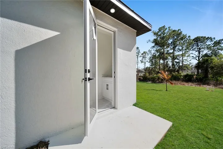 Property entrance featuring a yard, a patio area, and stucco siding