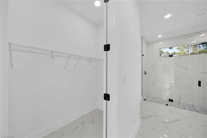 Full bathroom featuring a spacious closet, recessed lighting, a marble finish shower, and marble finish floors