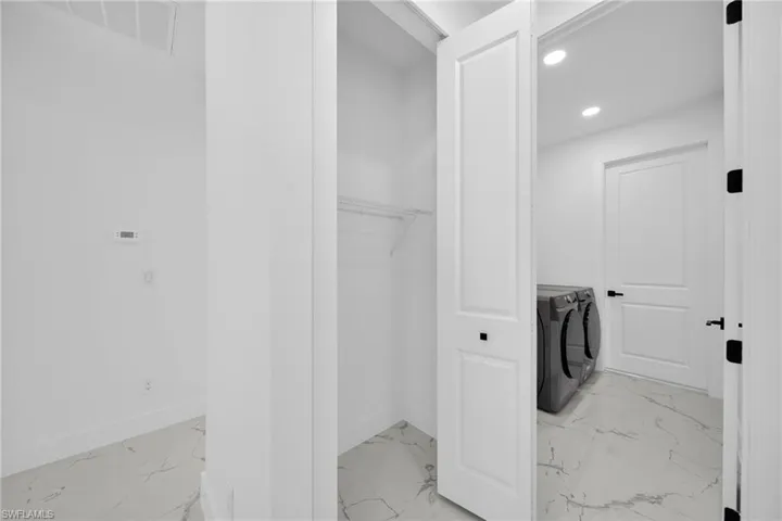 Laundry area with washing machine and dryer, light marble finish flooring, and recessed lighting