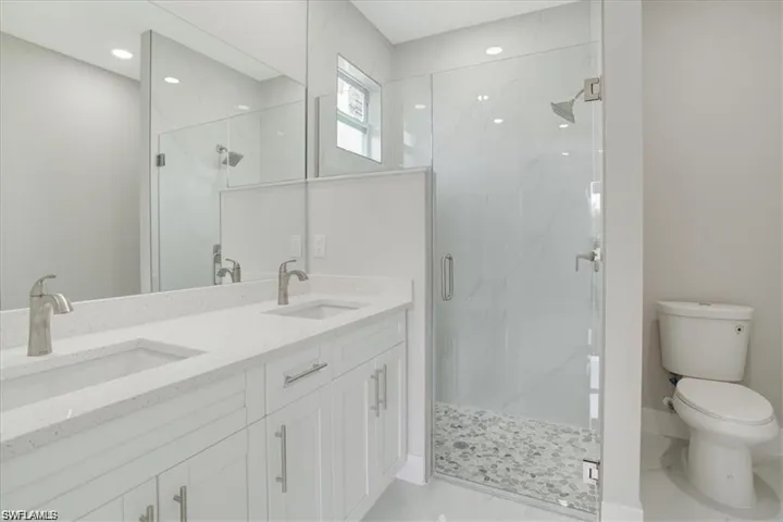 Bathroom featuring toilet, vanity, and a shower with shower door