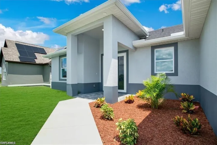 Entrance to property featuring solar panels and a lawn