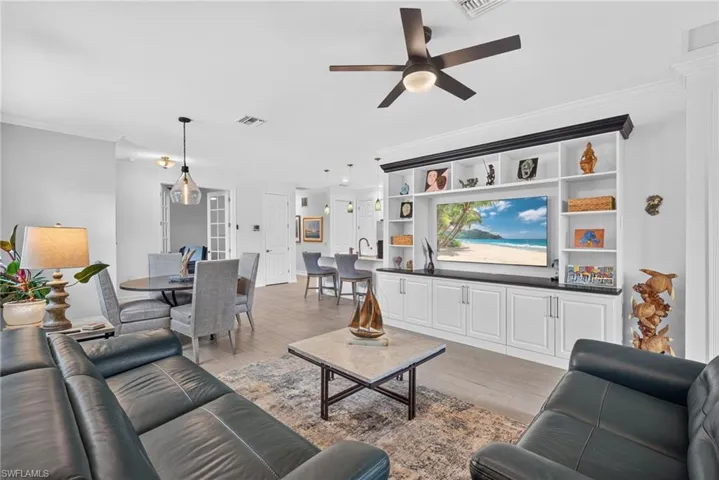 Integrated entertainment center with built-in shelving, wood-finish flooring, recessed lighting, and crown molding