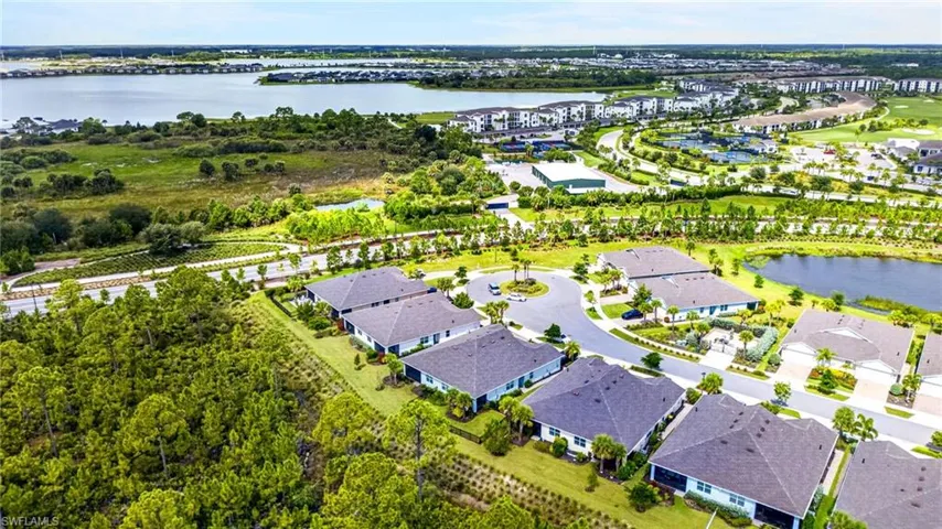 Aerial perspective showcasing a residential community with a large body of water, a circular street layout, and substantial green spaces
