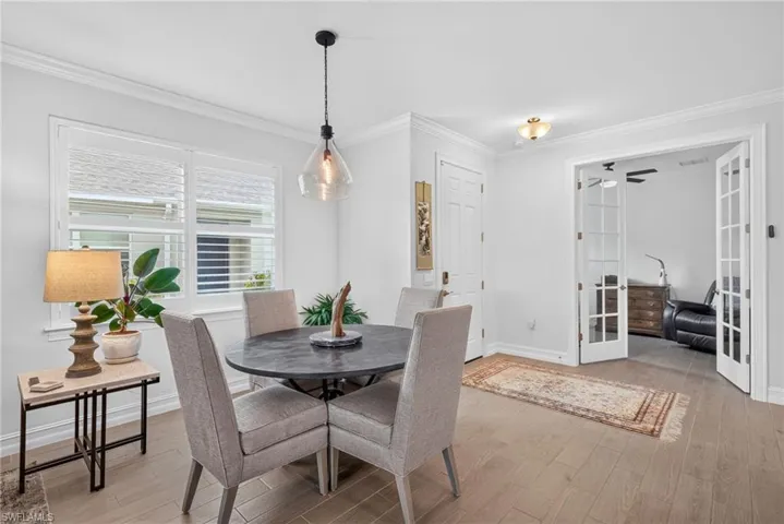 Wood-finish flooring, white plantation shutters, and a modern pendant light