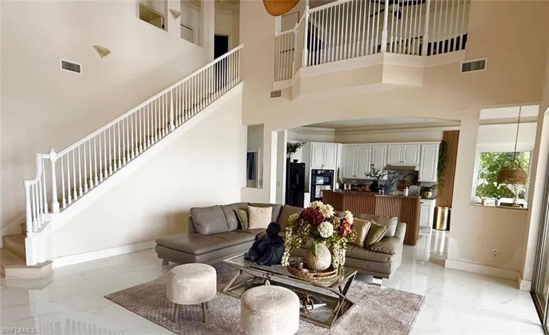 Living room with stairway, light marble finish flooring, and a high ceiling