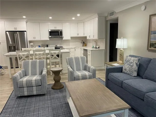 Living room featuring recessed lighting, light wood-style flooring, and ornamental molding