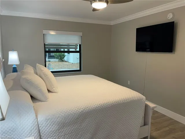 Bedroom featuring crown molding, wood finished floors, and ceiling fan