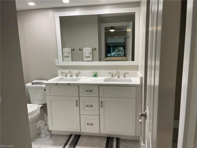 Bathroom with light marble finish floors and double vanity