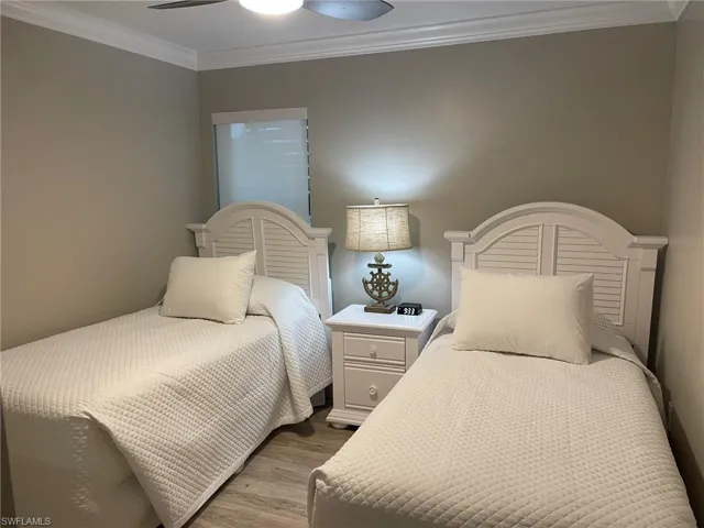Bedroom with ornamental molding, a ceiling fan, and wood finished floors