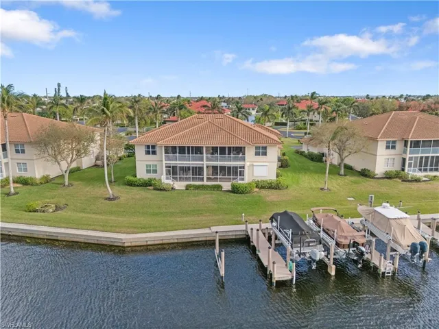 Back of house featuring a sunroom, a water view, and a yard