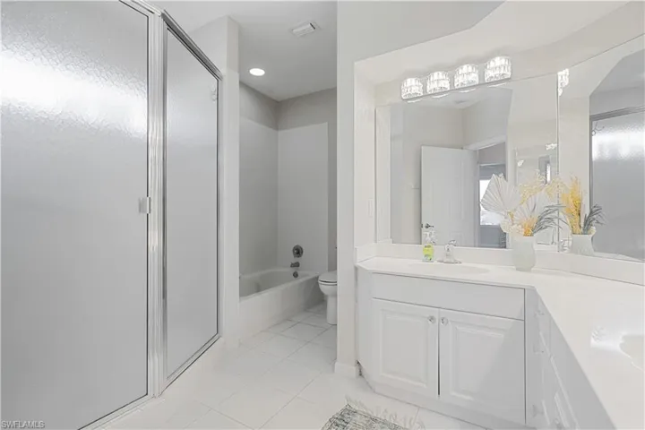 Full bathroom featuring toilet, vanity, tile patterned floors, and independent shower and bath