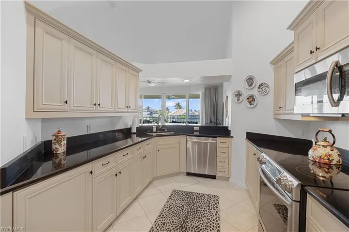 Kitchen with appliances with stainless steel finishes, sink, cream cabinetry, and light tile patterned floors