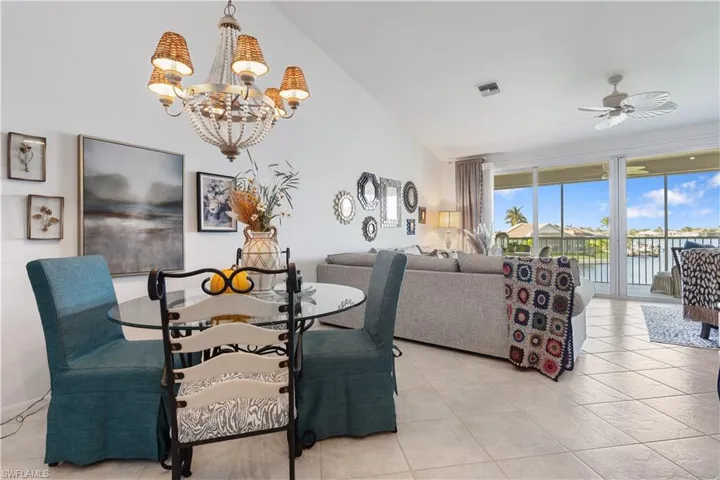 Dining room featuring lofted ceiling, light tile patterned floors, and ceiling fan with notable chandelier