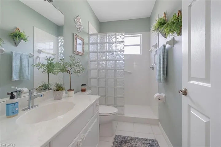 Bathroom with vanity, tile patterned floors, toilet, and tiled shower