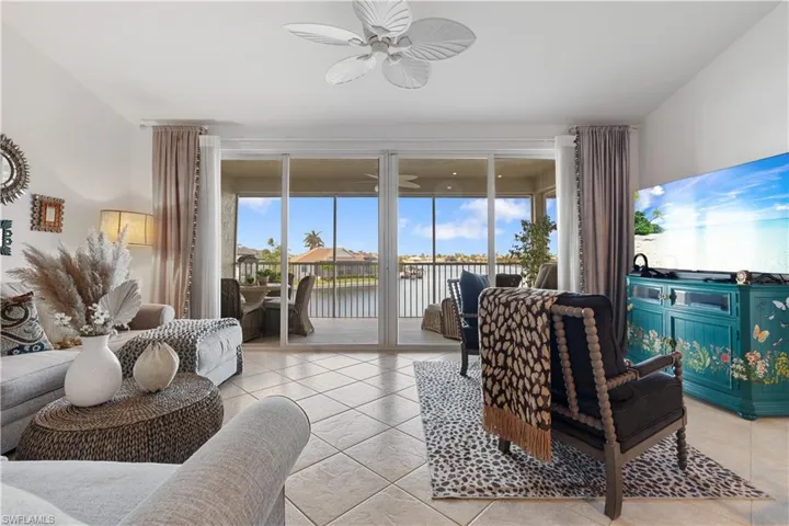Living room with a wealth of natural light, light tile patterned floors, and ceiling fan